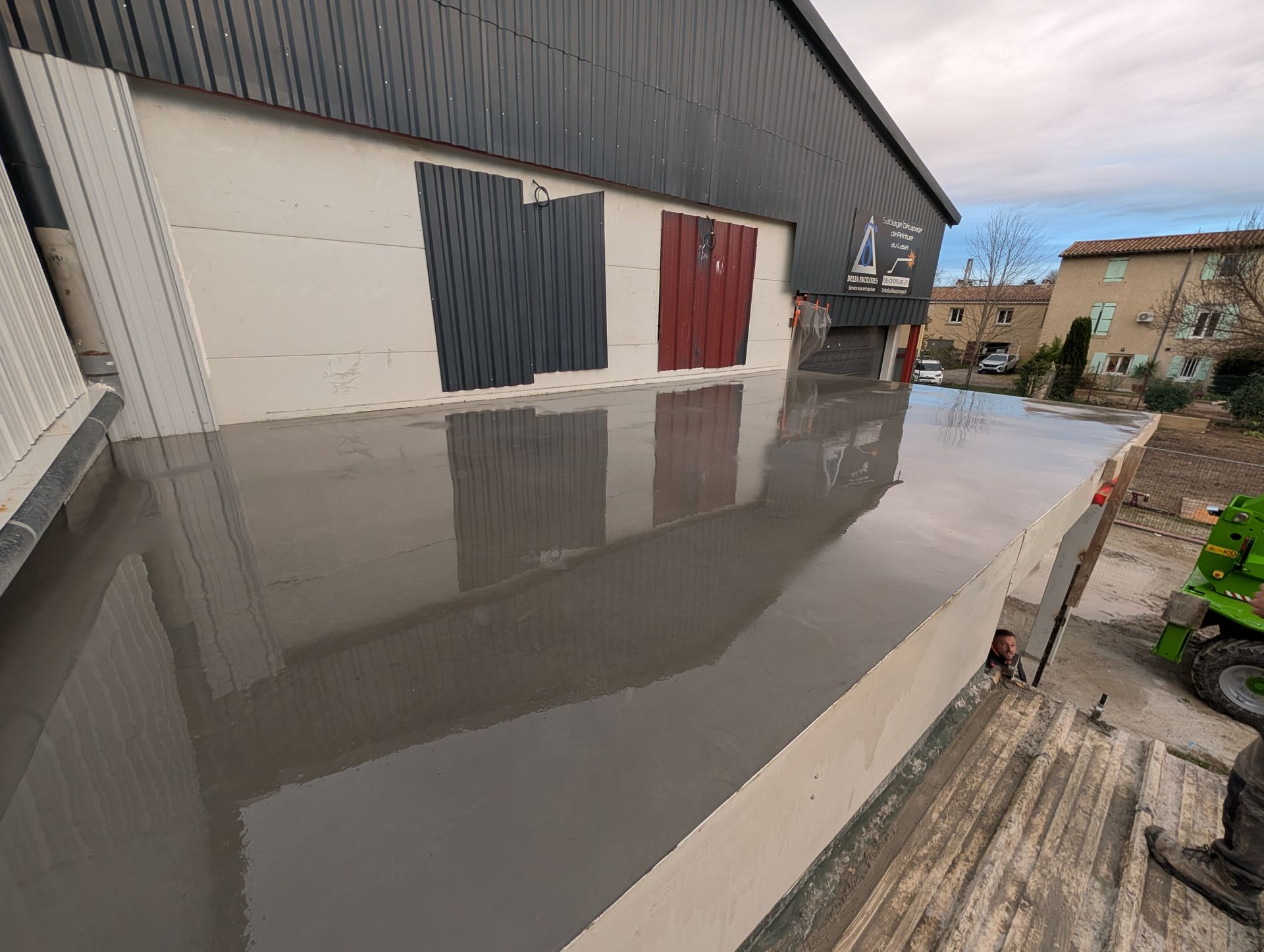 Fondations en béton avec barres d'armature devant un bâtiment aux grandes fenêtres. 