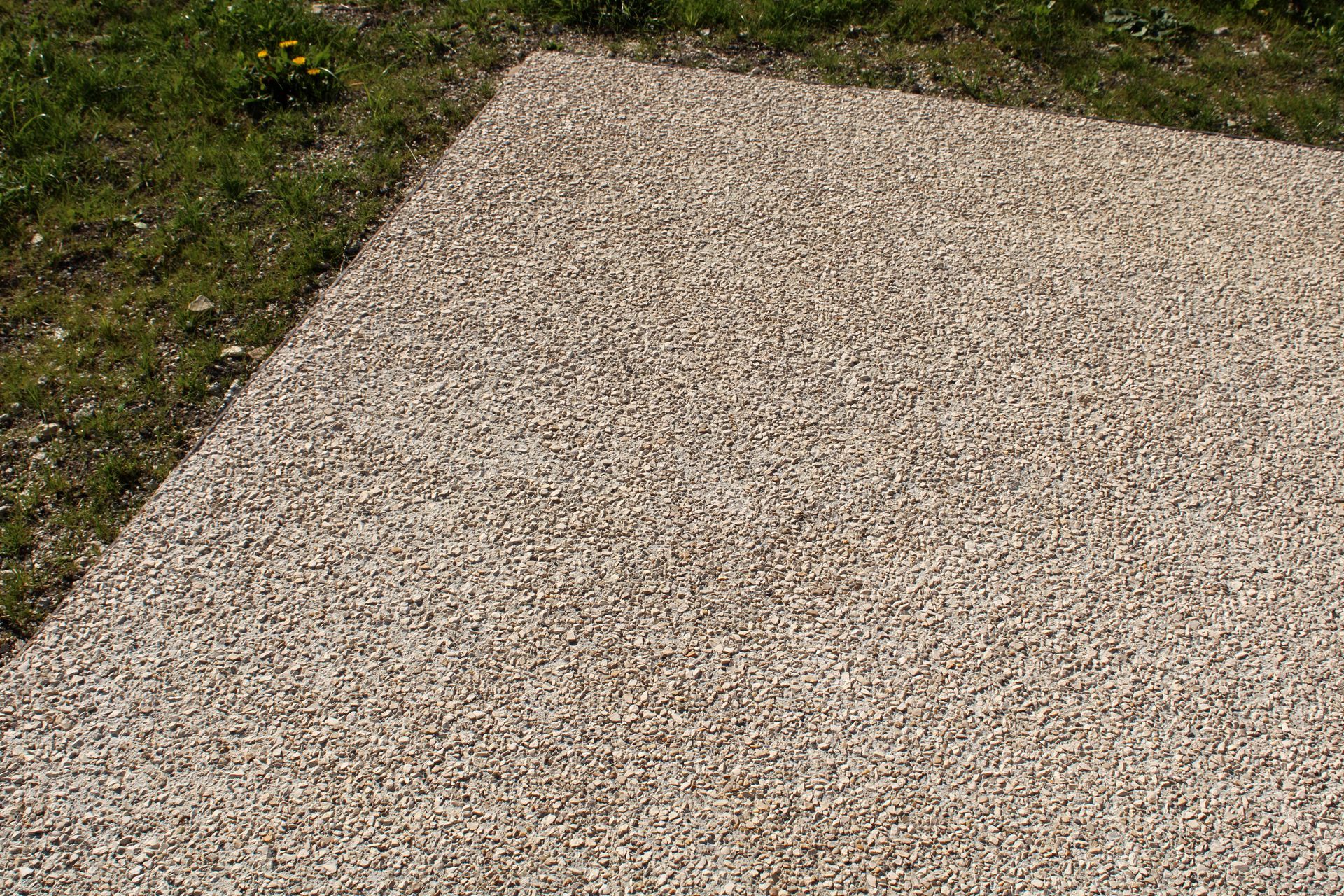 Revêtement en gravier beige à côté de l'herbe verte.