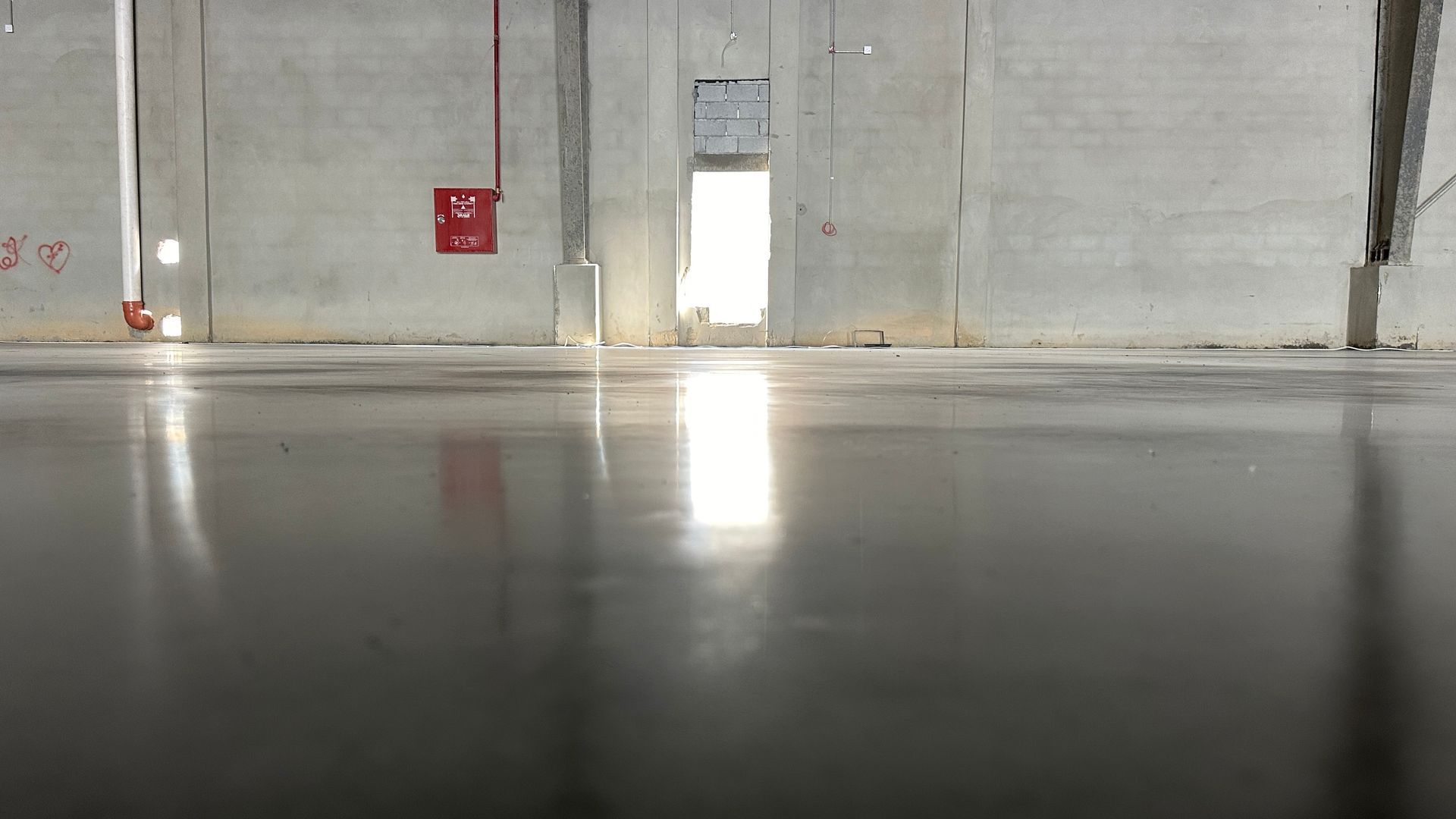 Sol en béton brillant et réfléchissant dans un grand entrepôt vide.