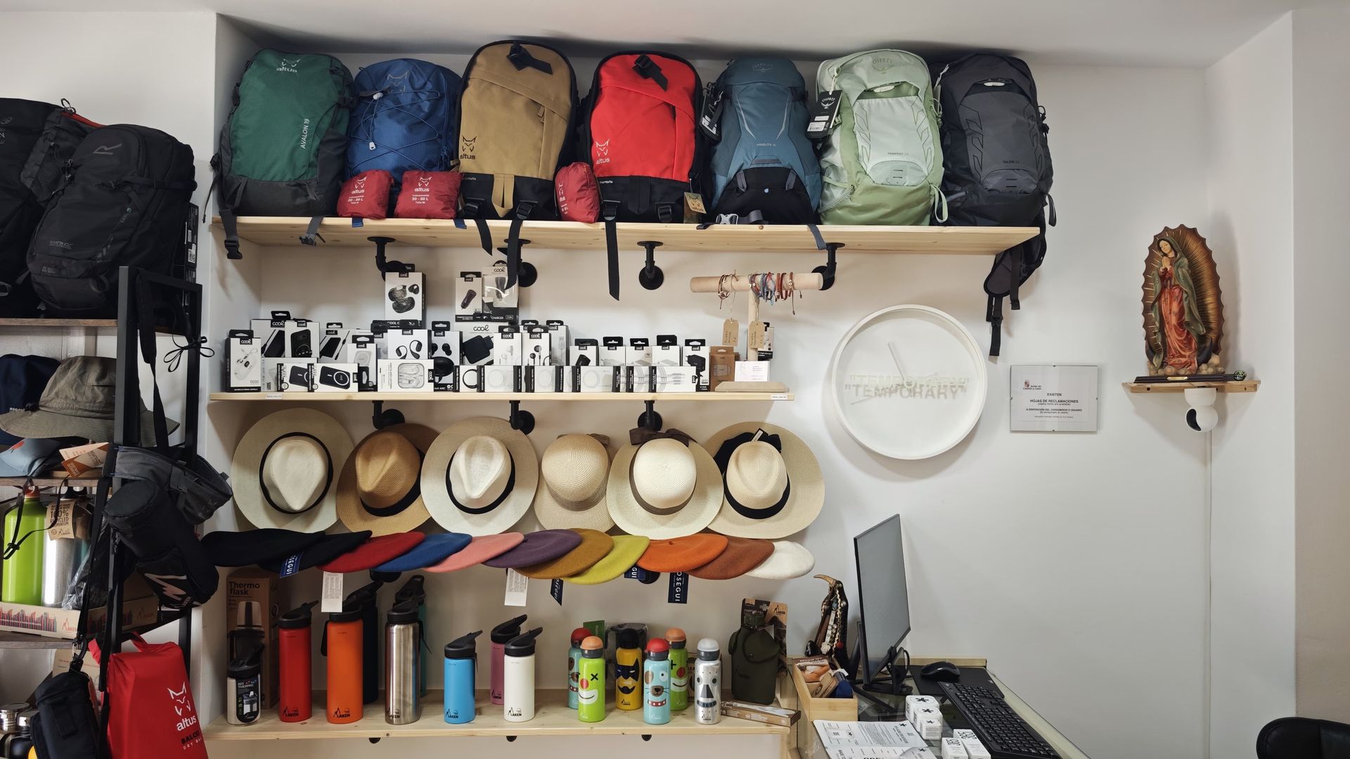Estantes con equipo de camping, sombreros, botellas y utensilios colgantes en una zona de almacenamiento compacta