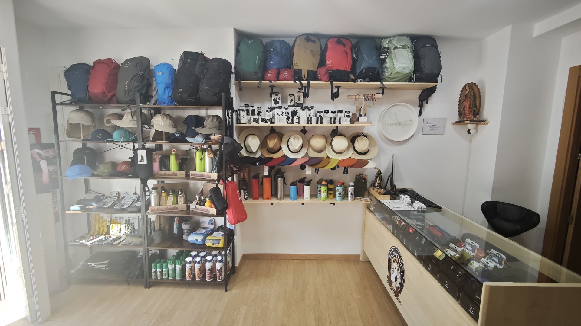 Interior de una tienda de artículos de aventura con mochilas, sombreros, tazas y recuerdos exhibidos en estantes