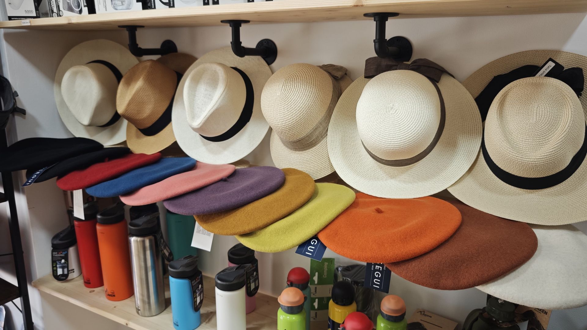 Estantes con sombreros de paja y sombreros de colores expuestos en una tienda o puesto de mercado