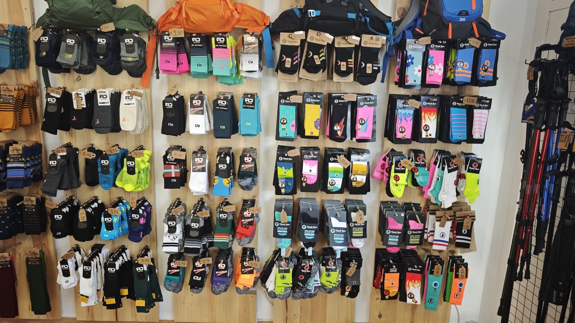 Una pared de calcetines de colores para mascotas, expuestos en estantes de tienda, con correas colgadas a la derecha.
