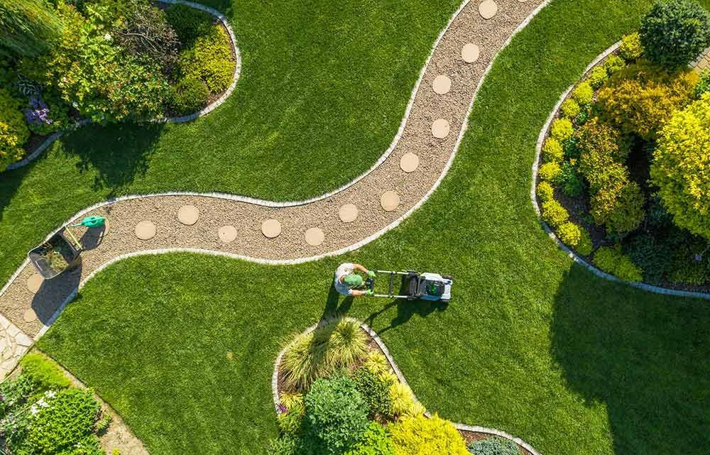 eine Luftaufnahme einer Person , die einen Rasenmäher in einem Garten benutzt .