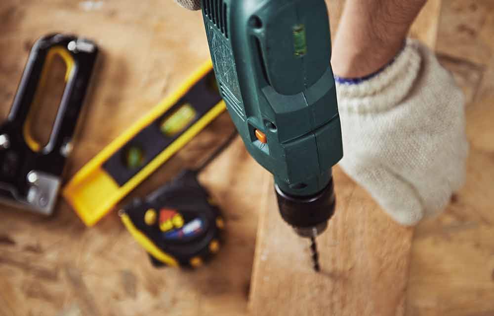 Ein Mann bohrt in ein Stück Holz mit einem Bohrer .