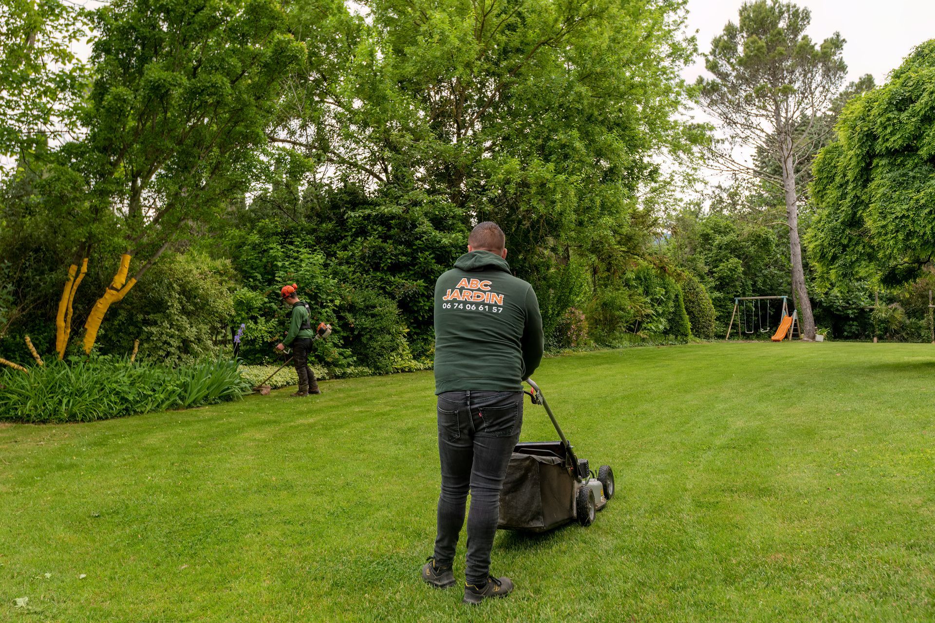 Paysagiste de dos avec une tondeuse à gazon