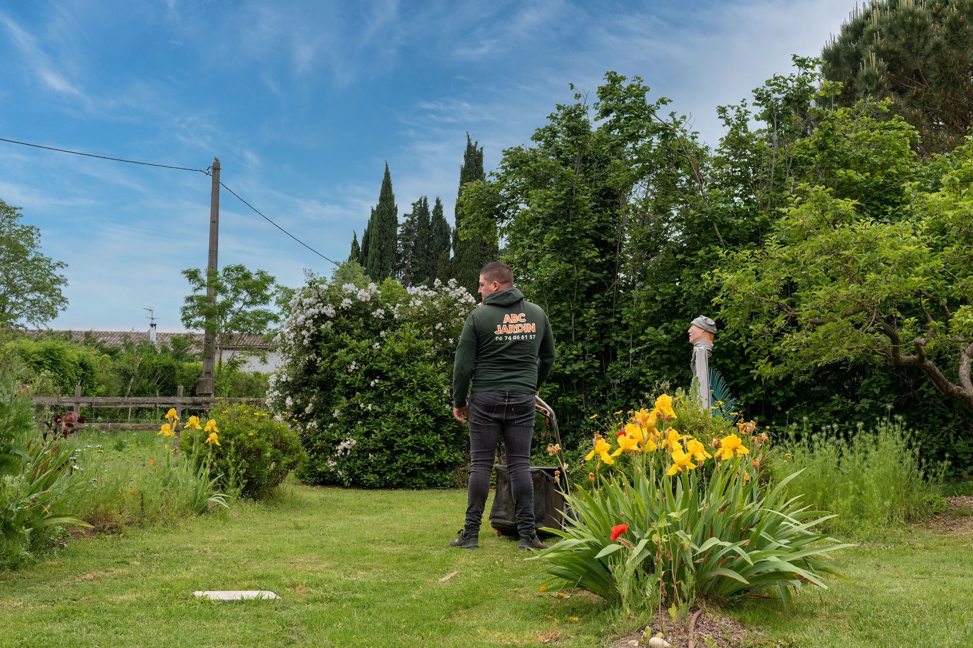 Paysagiste de dos avec une tondeuse à l'arrêt dans un jardin