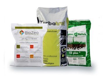 Tres bolsas de fertilizante están una al lado de la otra sobre una superficie blanca.