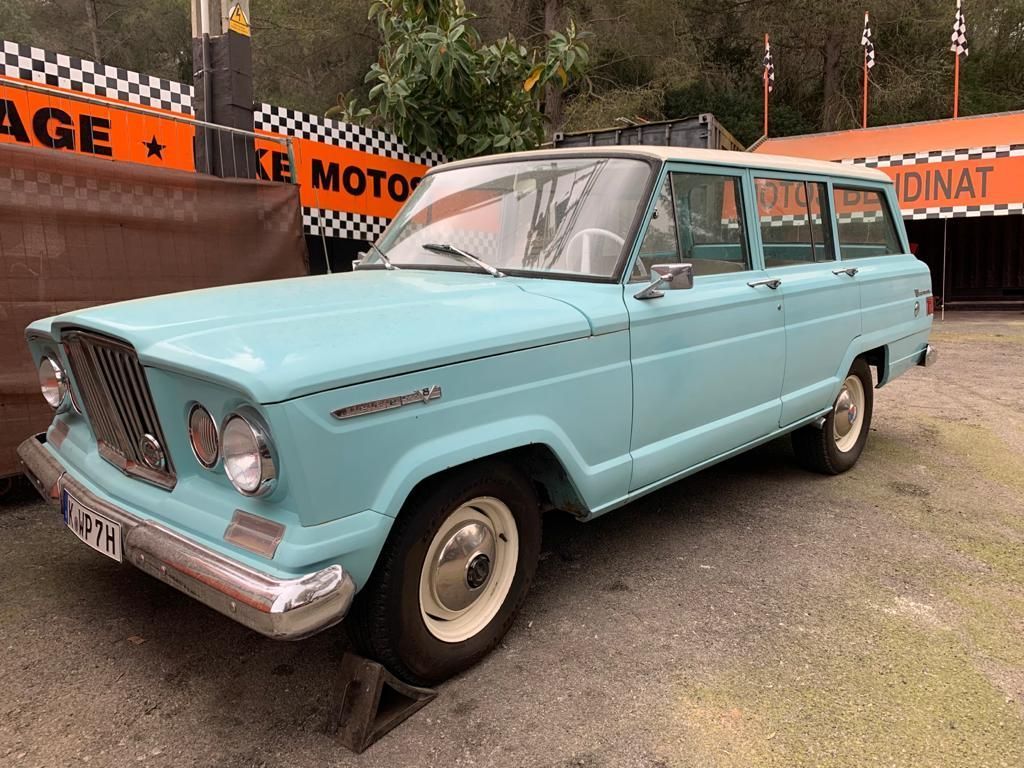Un jeep azul está estacionado frente a un garaje.