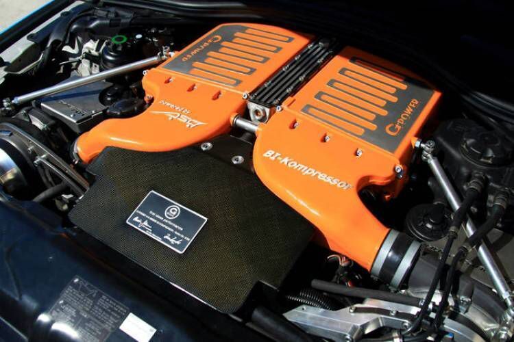 Un primer plano de un motor de automóvil con dos conectores naranjas unidos a él.