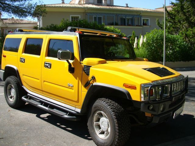 Una camioneta Hummer H2 amarilla está estacionada al costado de la carretera.