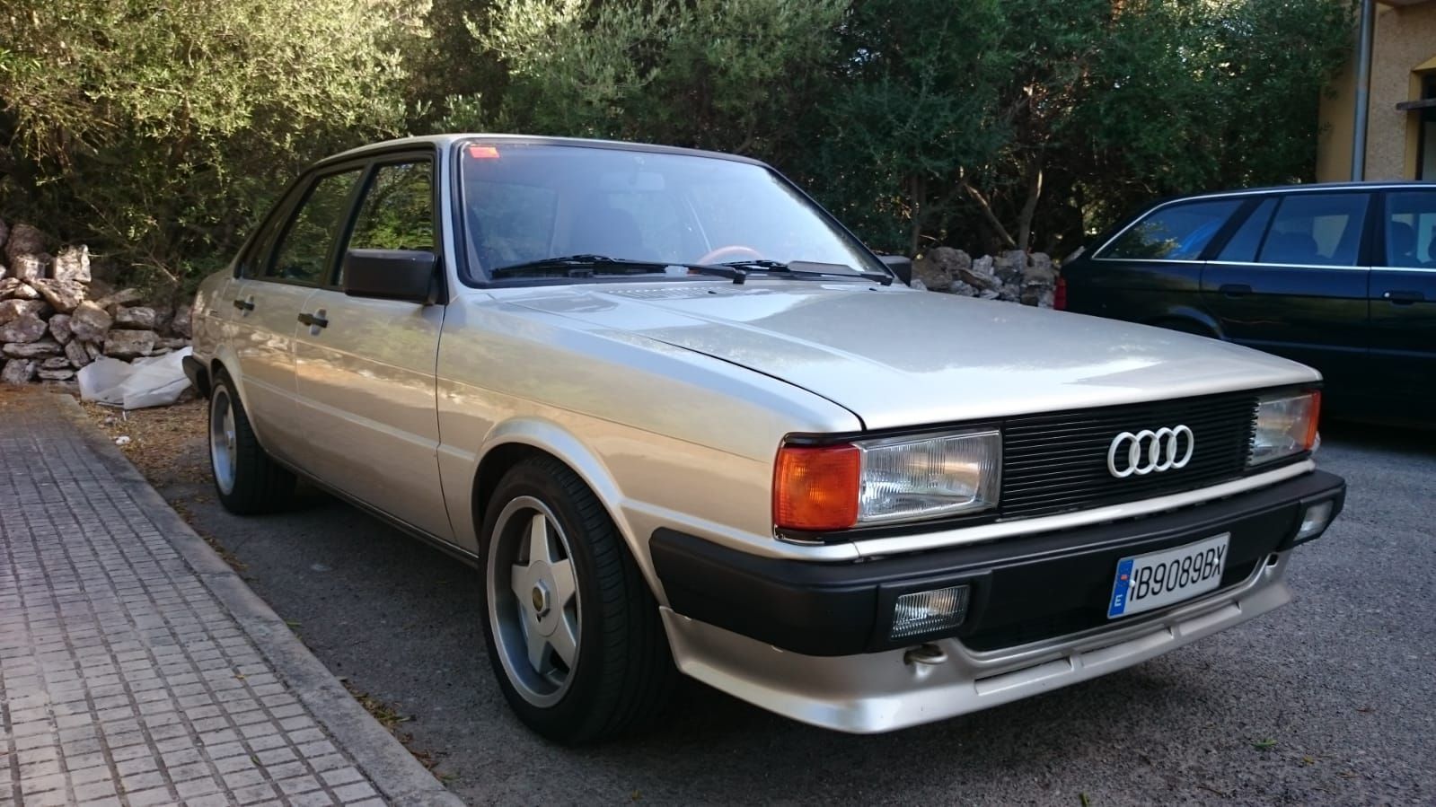 Un coche blanco está aparcado al costado de la carretera.