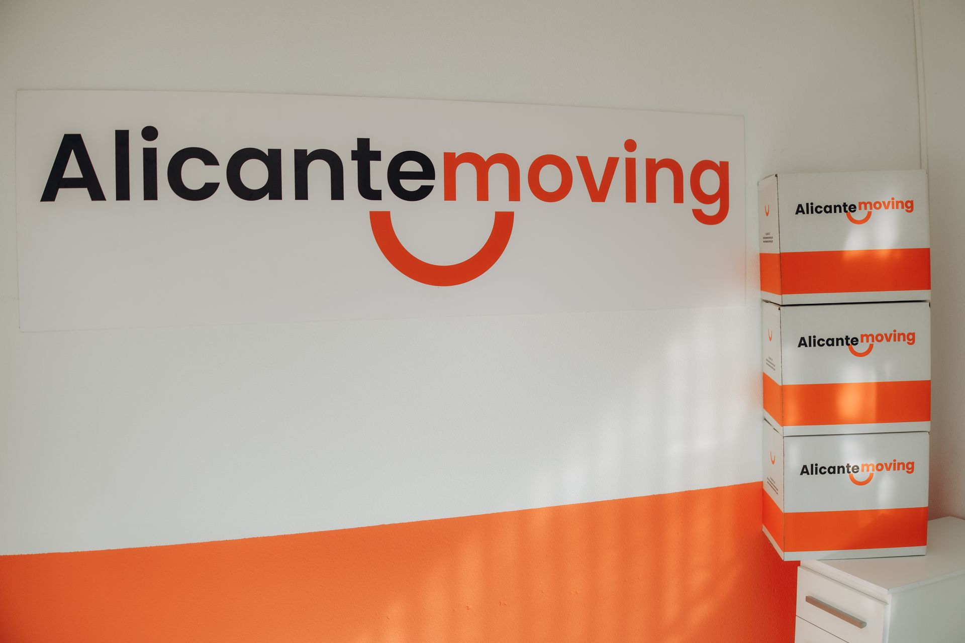 Paseo costero con palmeras, edificios y un castillo en lo alto de una colina rocosa bajo un cielo azul.