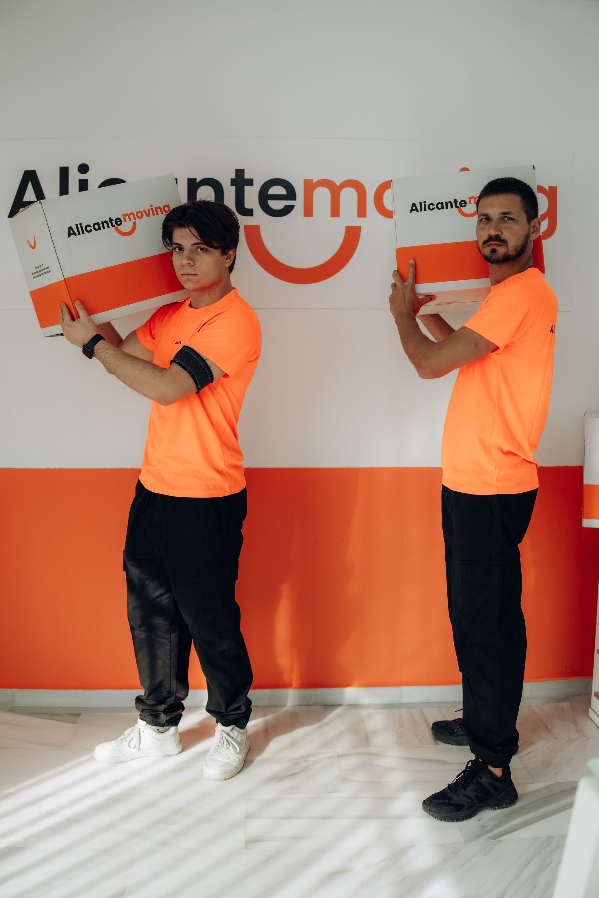 Paseo marítimo con palmeras a lo largo de una bahía. Edificios y una colina rocosa al fondo. Día soleado.