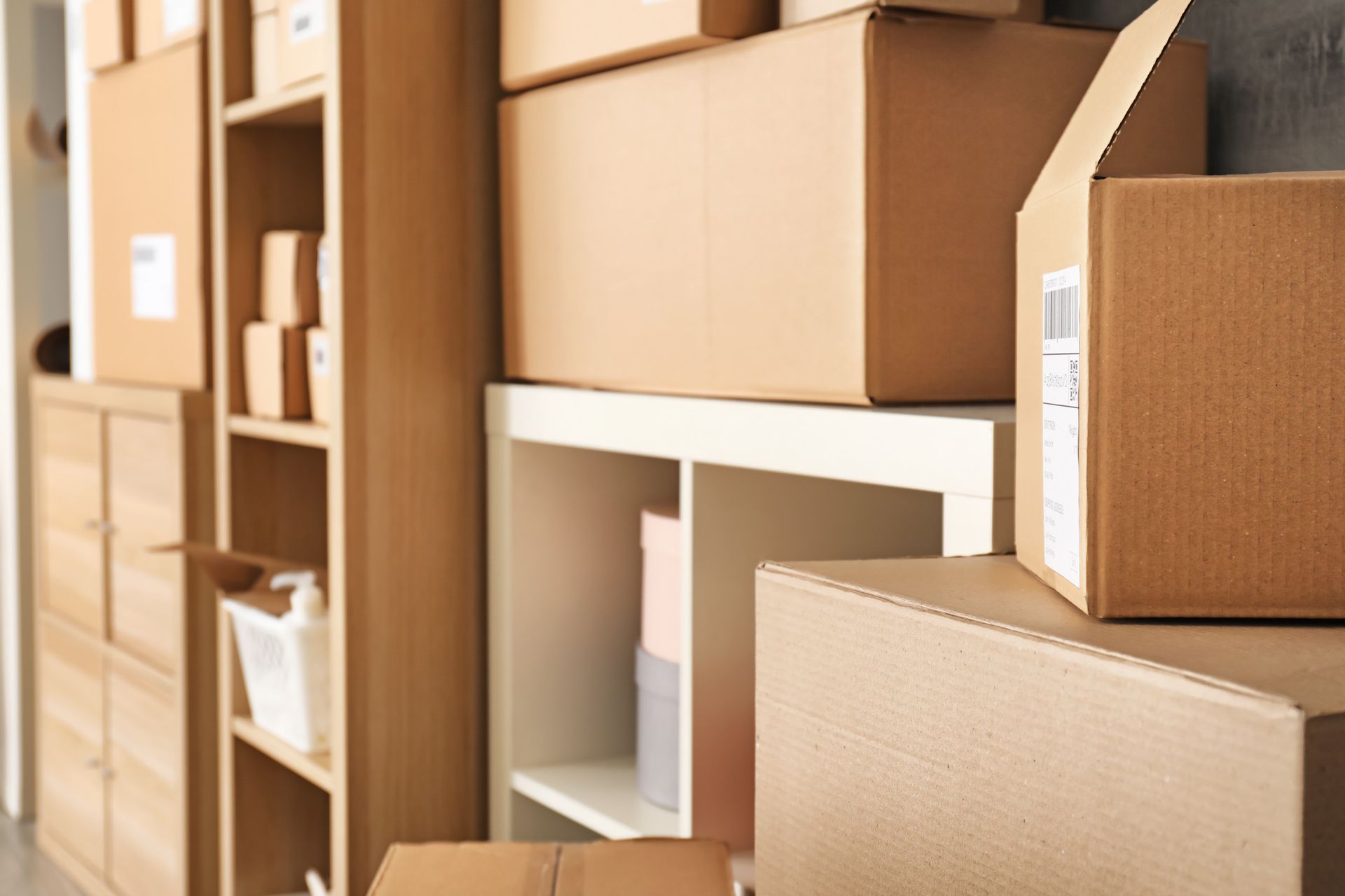 Cajas de cartón apiladas en estantes y un armario, posiblemente para almacenamiento o mudanza.