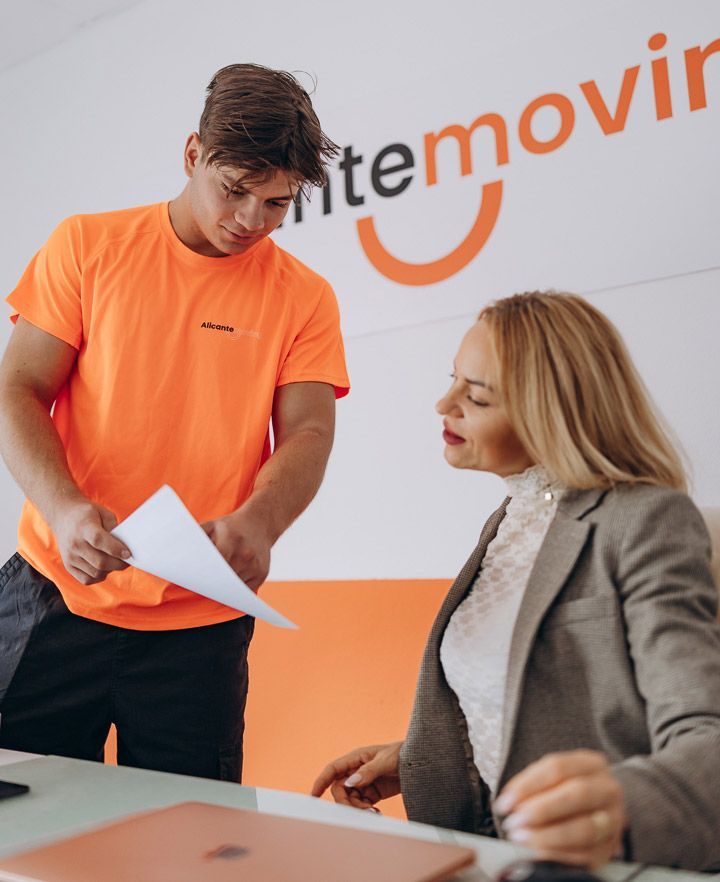 Los transportistas cargan cajas en una camioneta blanca estacionada sobre una superficie de ladrillo.