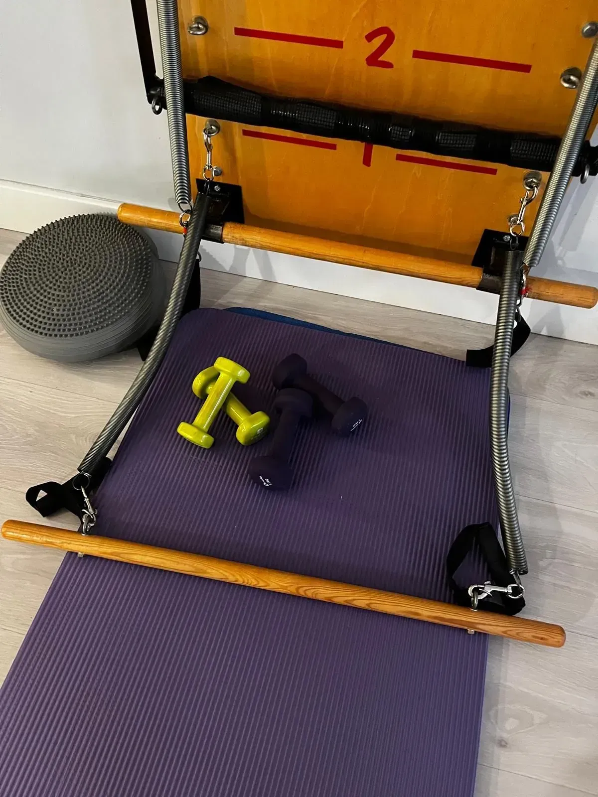 Reformer de pilates con pesas, pelota y colchoneta. Equipo de entrenamiento en una sala.