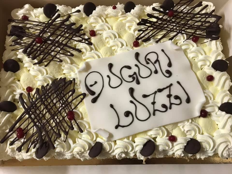 Torta rettangolare decorata con glassa bianca, gocce di cioccolato