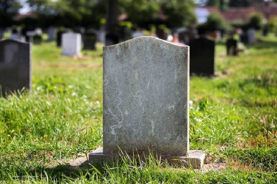 Grab mit hellem Grabstein auf einem Friedhof