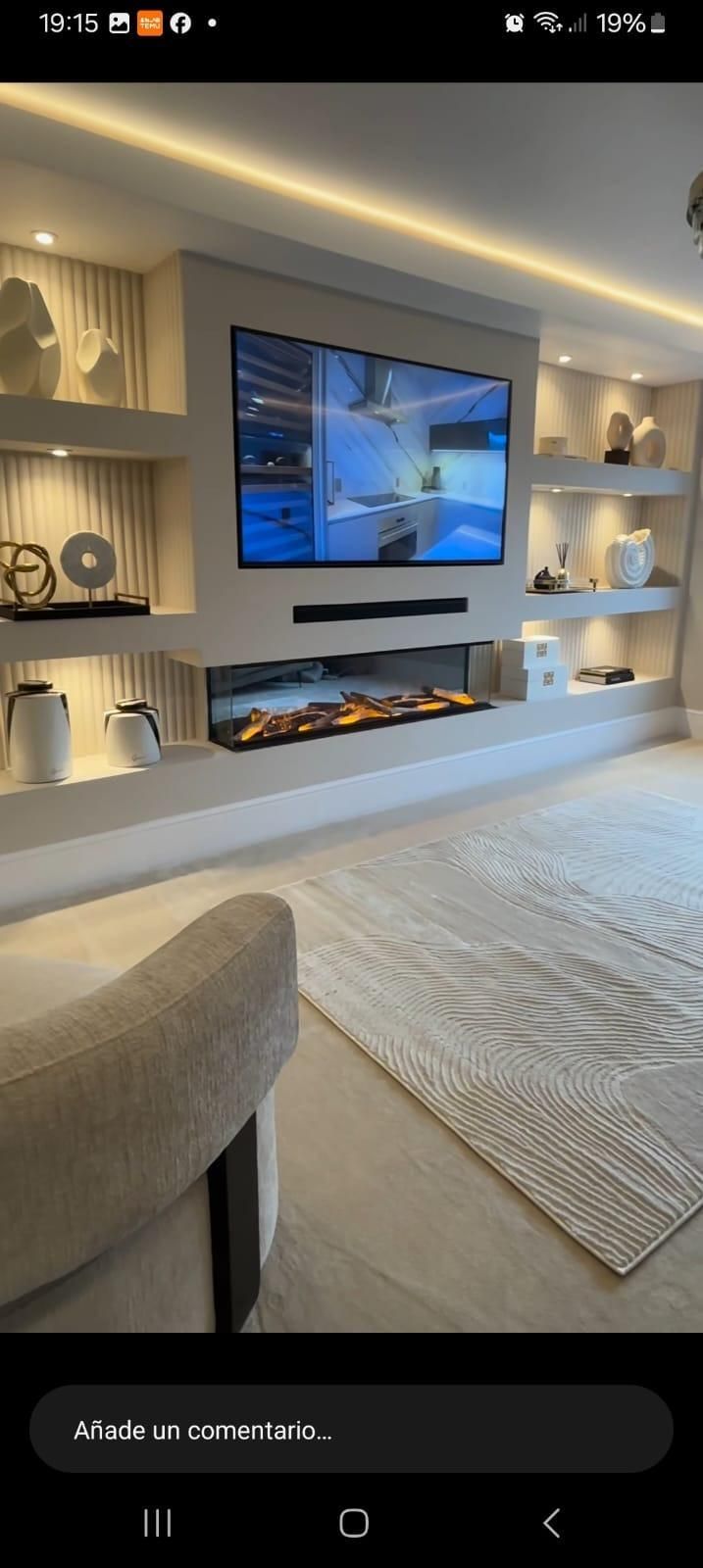 Sala de estar moderna con televisor montado en la pared sobre la chimenea, estanterías