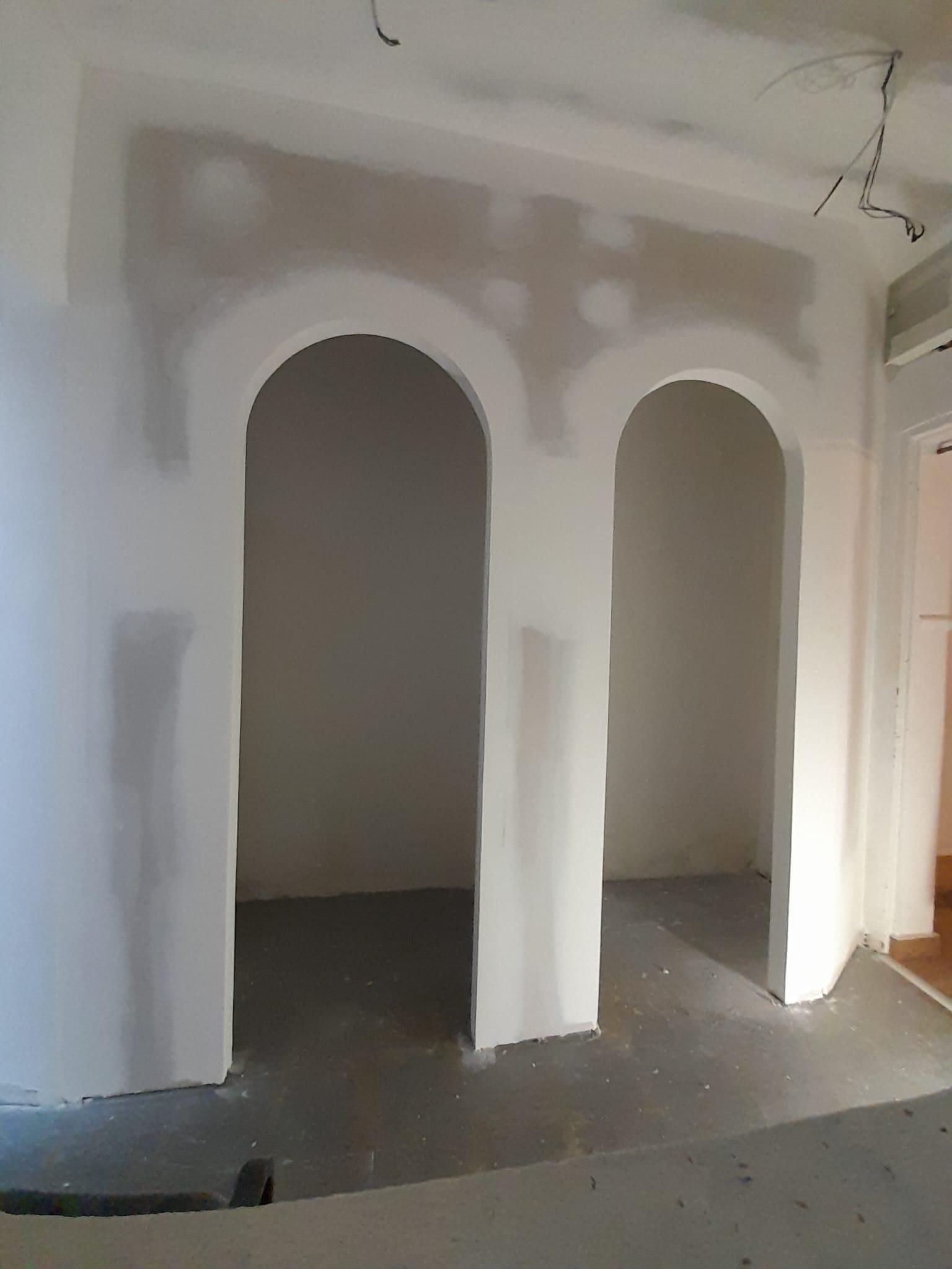 Dos arcos de puerta sin terminar, excavados en una pared cubierta de masilla gris fresca.