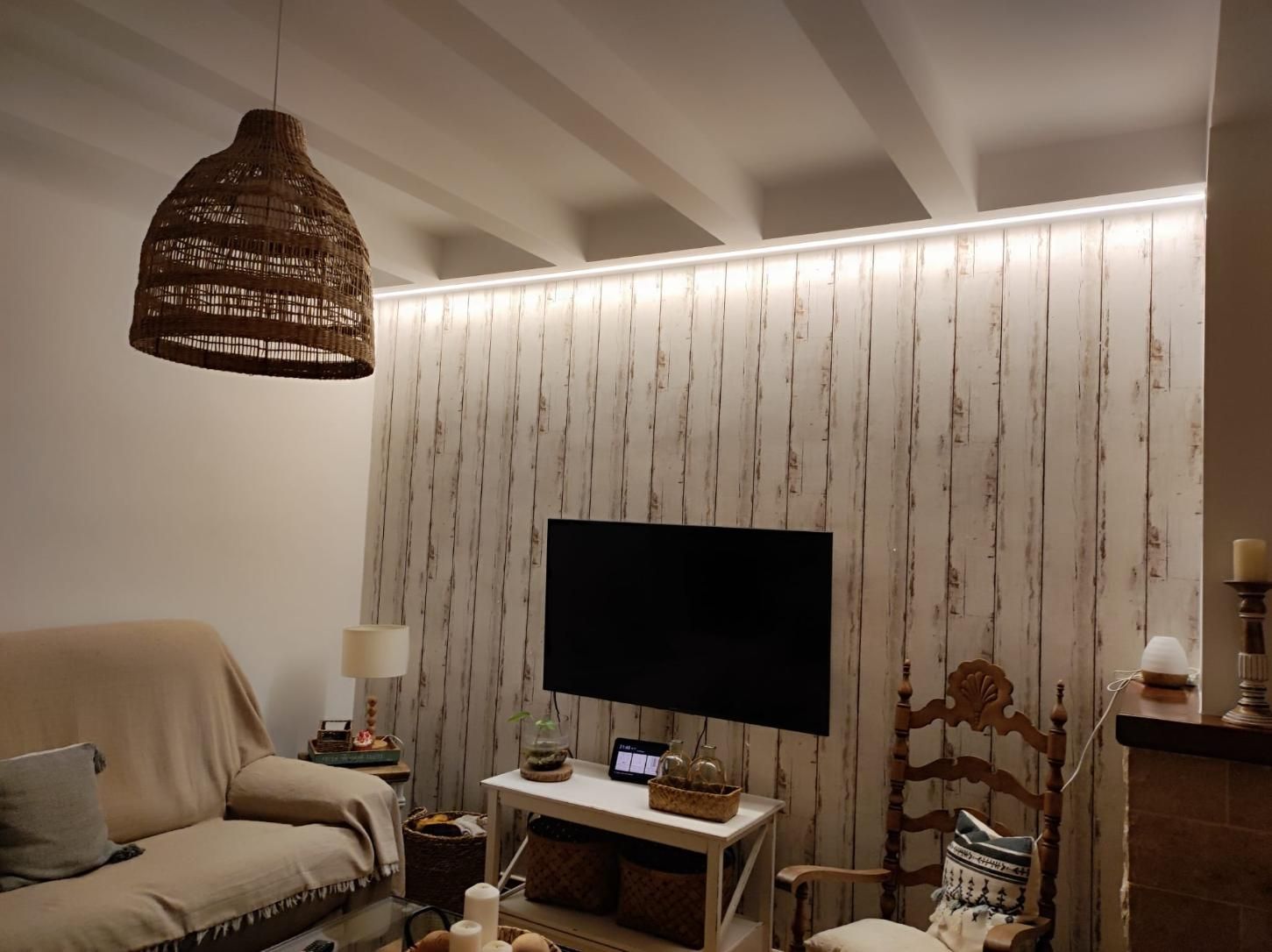 Una acogedora sala de estar con una pared revestida de paneles de madera texturizada de color claro