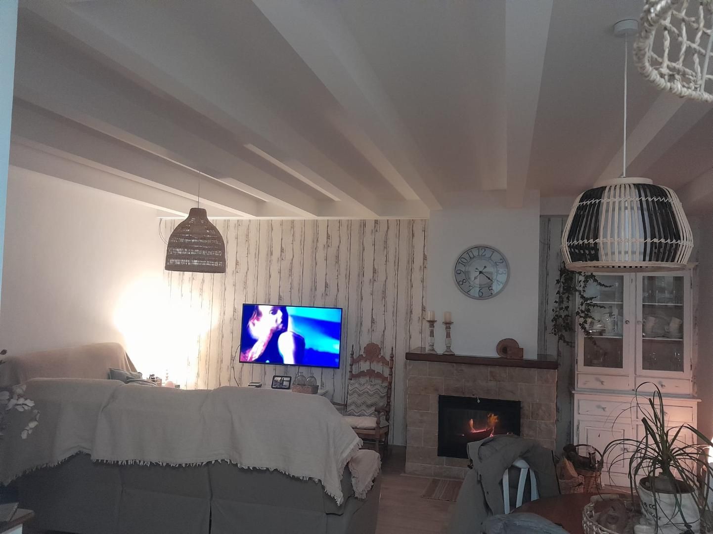 Una acogedora sala de estar con un sofá tapizado, un televisor en una pared decorada con motivos, una chimenea de piedra
