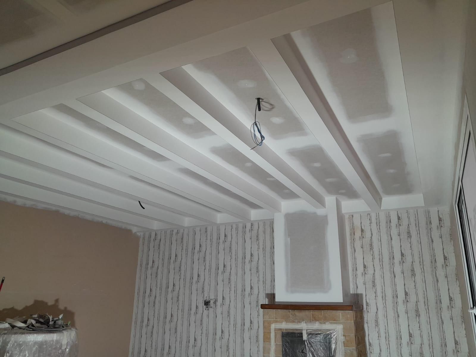 Una habitación con techo artesonado que deja ver la cinta de yeso y la masilla para juntas recién aplicadas