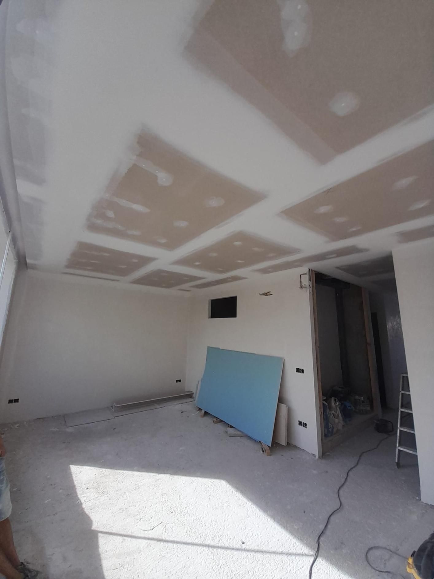 Una habitación sin terminar con placas de yeso recién instaladas y selladas con cinta adhesiva en el techo
