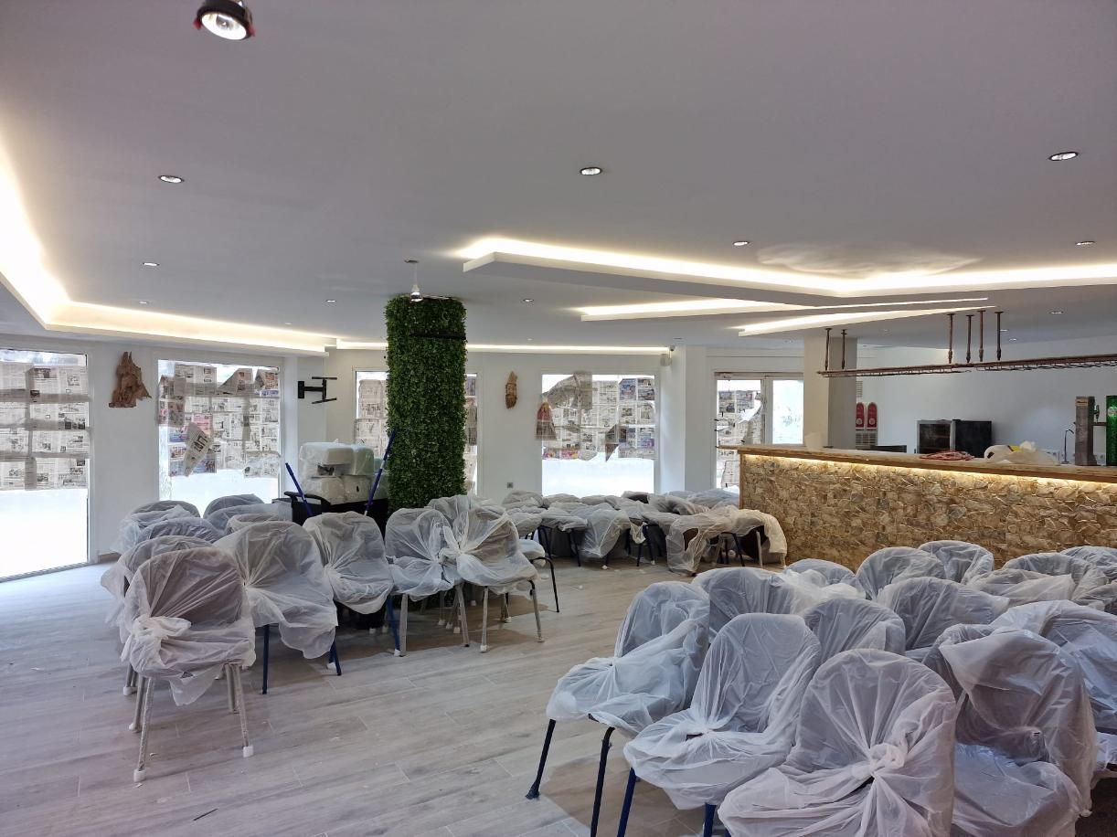 Una sala interior acondicionada para una presentación, con filas de sillas cubiertas con láminas de plástico