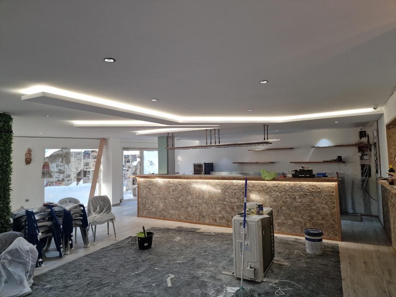 Un espacio de cafetería moderno y luminoso, con una barra texturizada, estanterías minimalistas