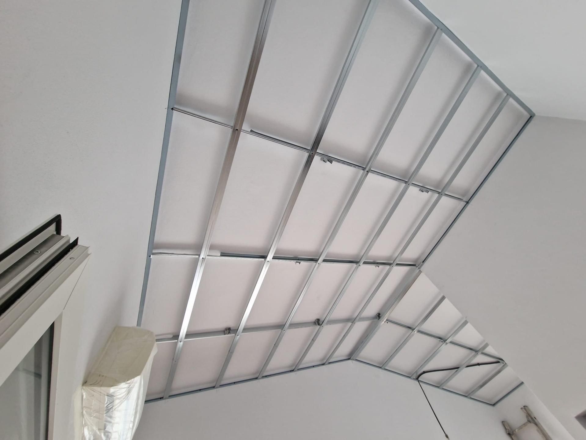 Una estructura metálica reticular instalada en un techo abovedado blanco, vista desde abajo 