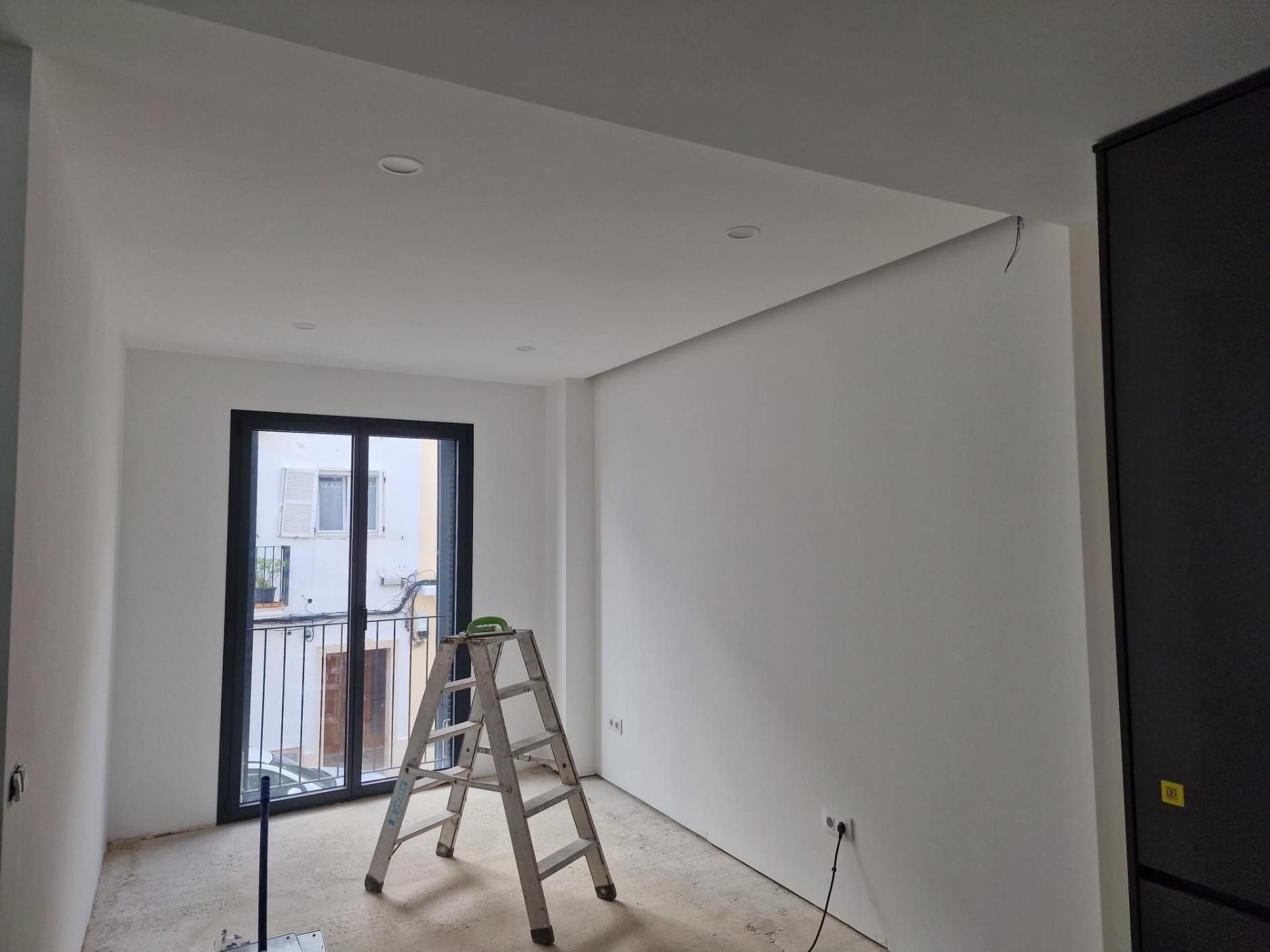 Escena de una reforma interior que muestra una escalera de mano en una habitación de paredes blancas