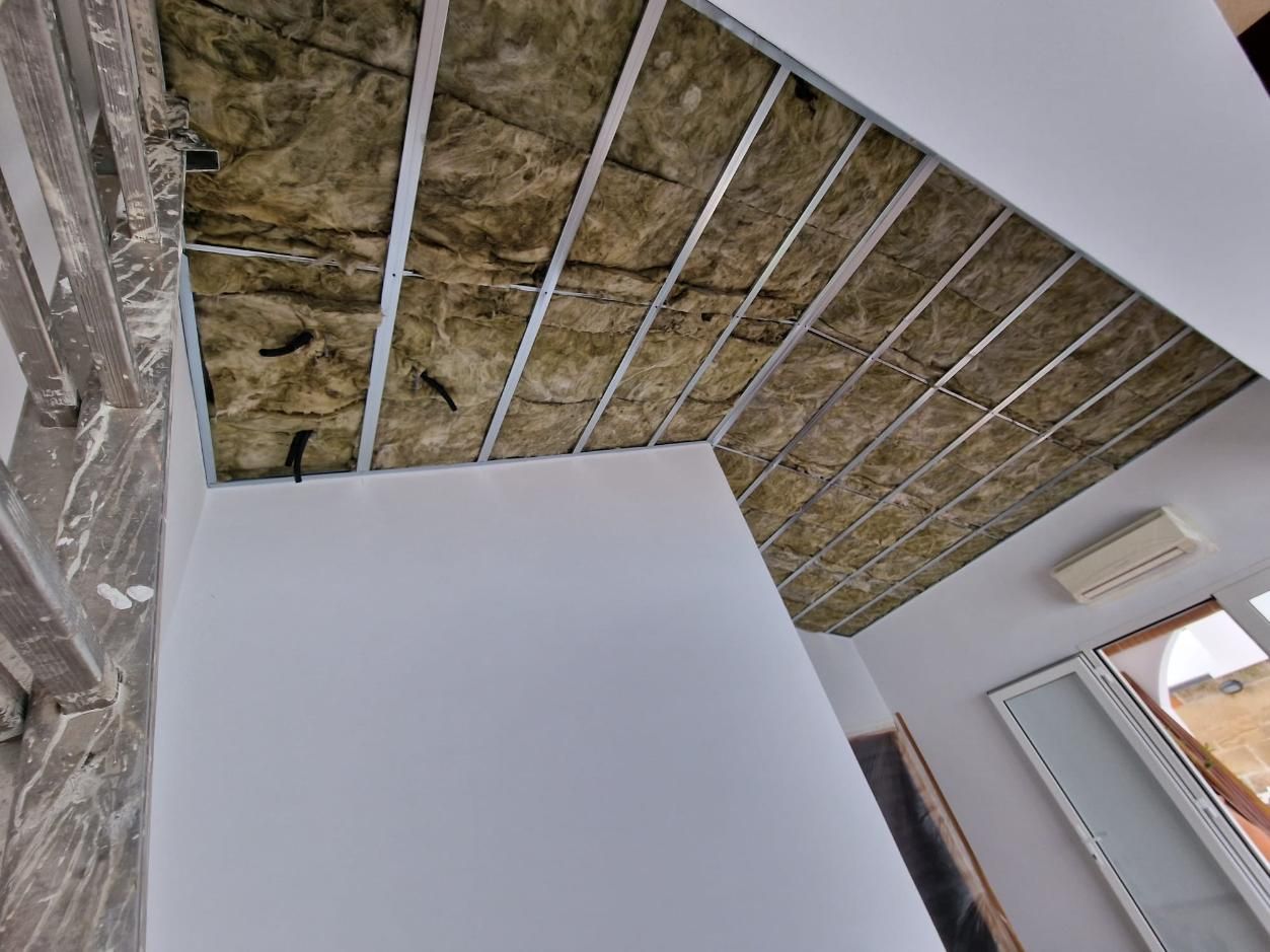 Techo de una habitación en construcción con estructura metálica a la vista y aislamiento térmico amarillo instalado.