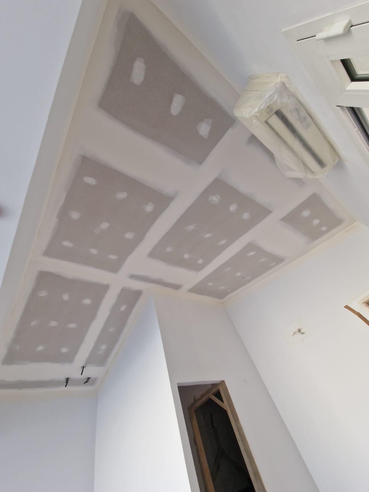 Un techo con paneles de yeso parcialmente instalados y juntas selladas con cinta adhesiva, l