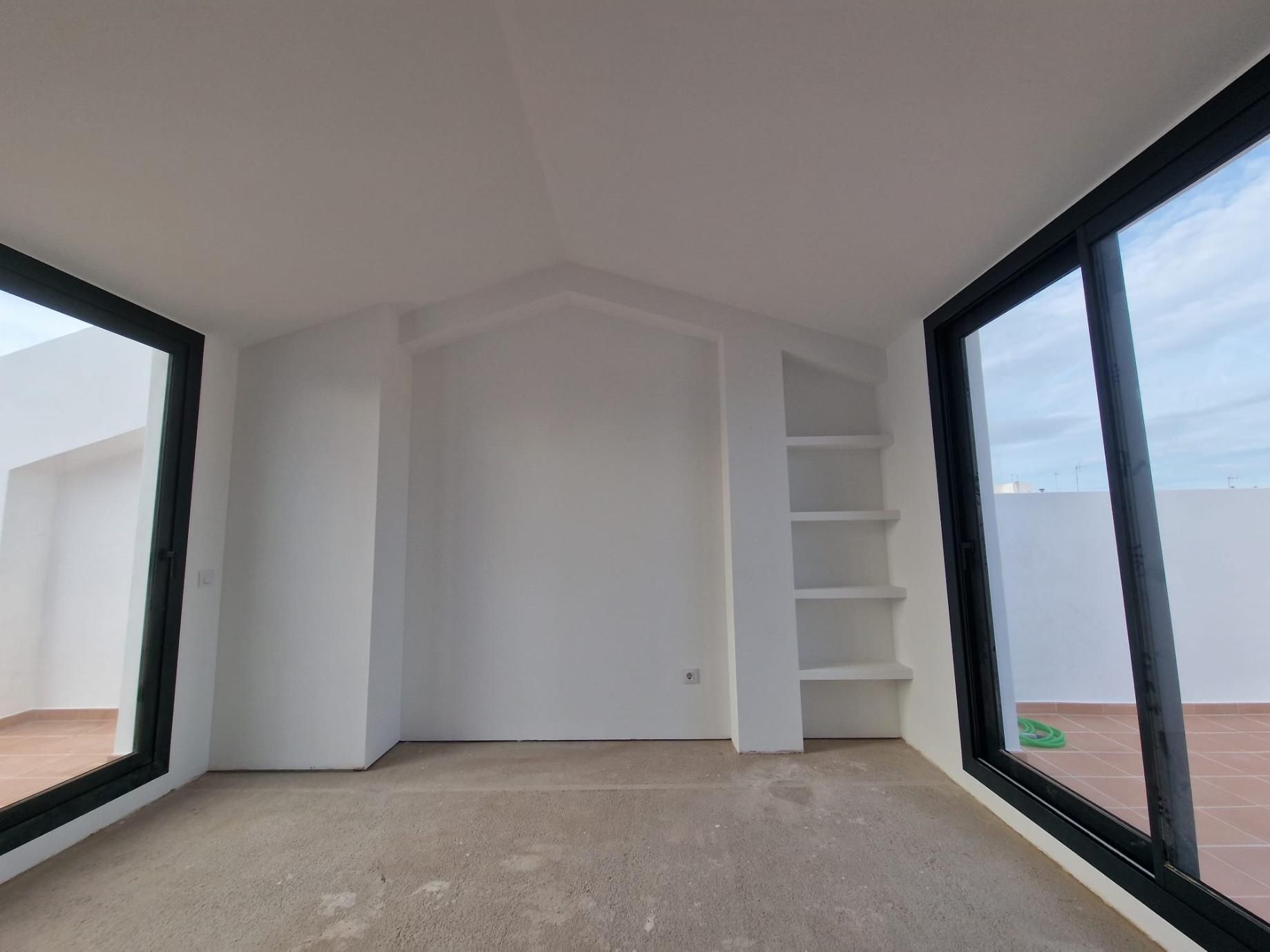 Una habitación interior con paredes blancas, suelo enmoquetado, estanterías empotradas