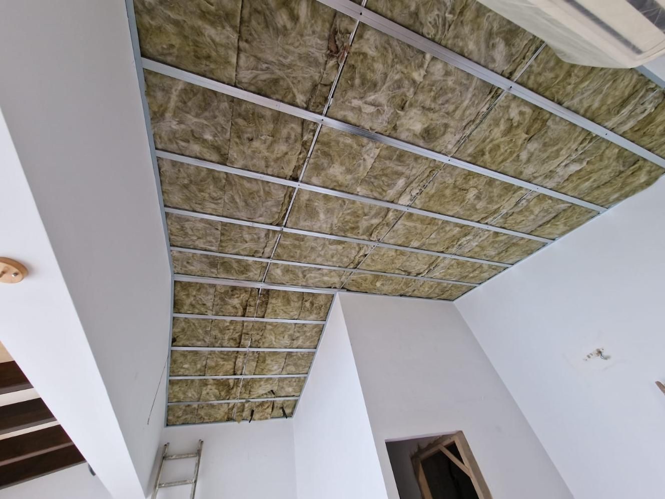 Un techo en construcción, con una estructura de rejilla metálica rellena de paneles aislantes amarillos.