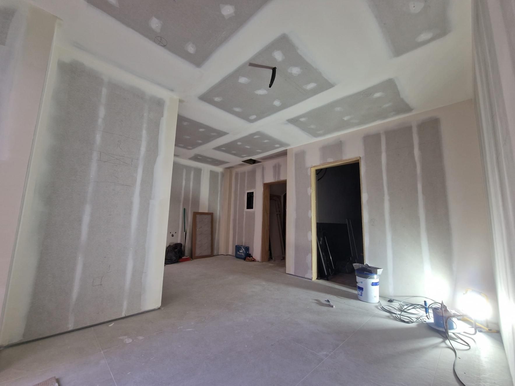 Una habitación interior en construcción con paredes y techo de pladur al descubierto, juntas selladas con cinta adhesiva