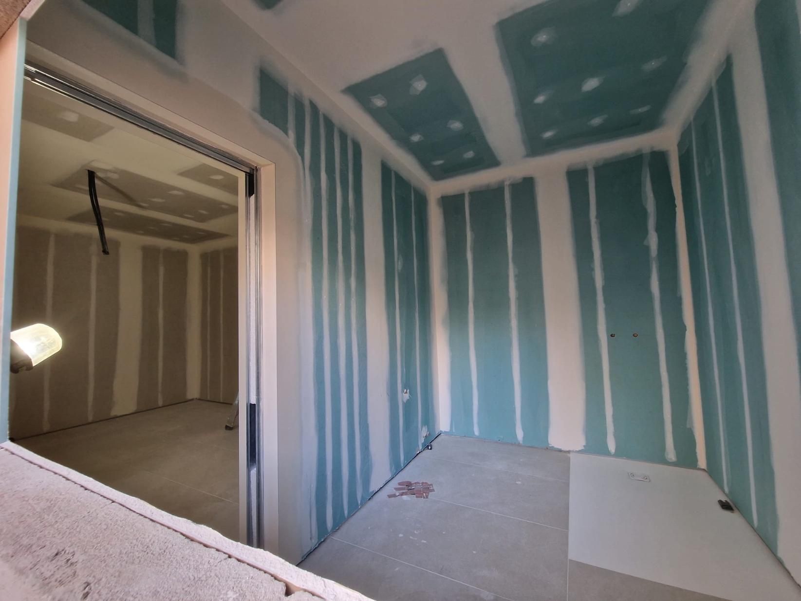 Una habitación interior en construcción con paneles de yeso resistentes a la humedad de color turquesa