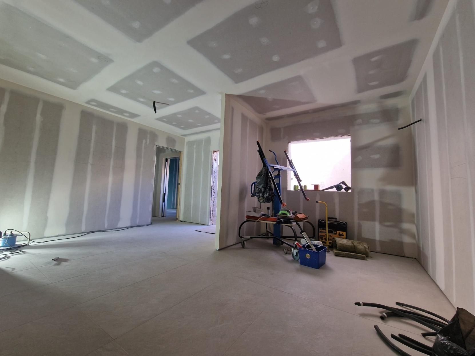 Interior de una habitación en construcción con paredes y techo de pladur al descubierto, una ventana