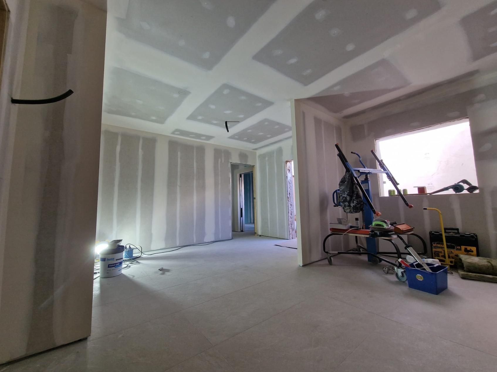 Vista interior de una habitación en construcción con paneles de yeso terminados