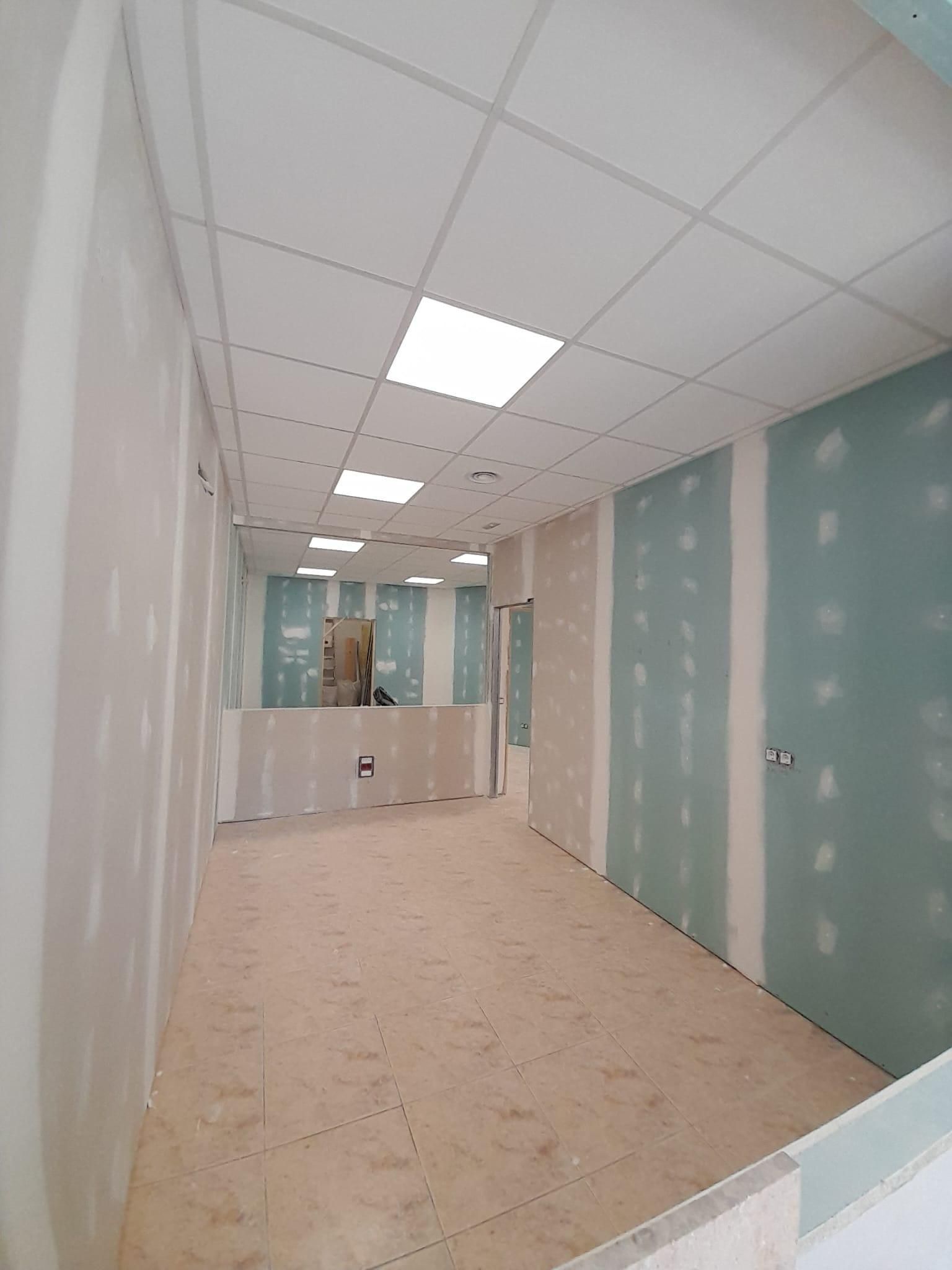Vista interior de un pasillo en construcción con paredes de pladur sin terminar, suelo de baldosas