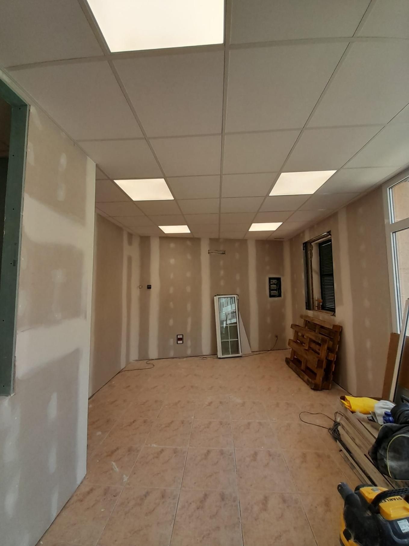 Una habitación sin terminar con paredes de pladur, un falso techo con luces empotradas