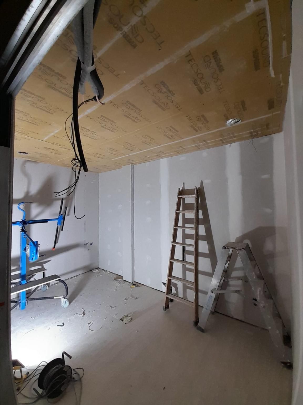 Una habitación interior en construcción con paneles de yeso en las paredes, aislamiento en el techo