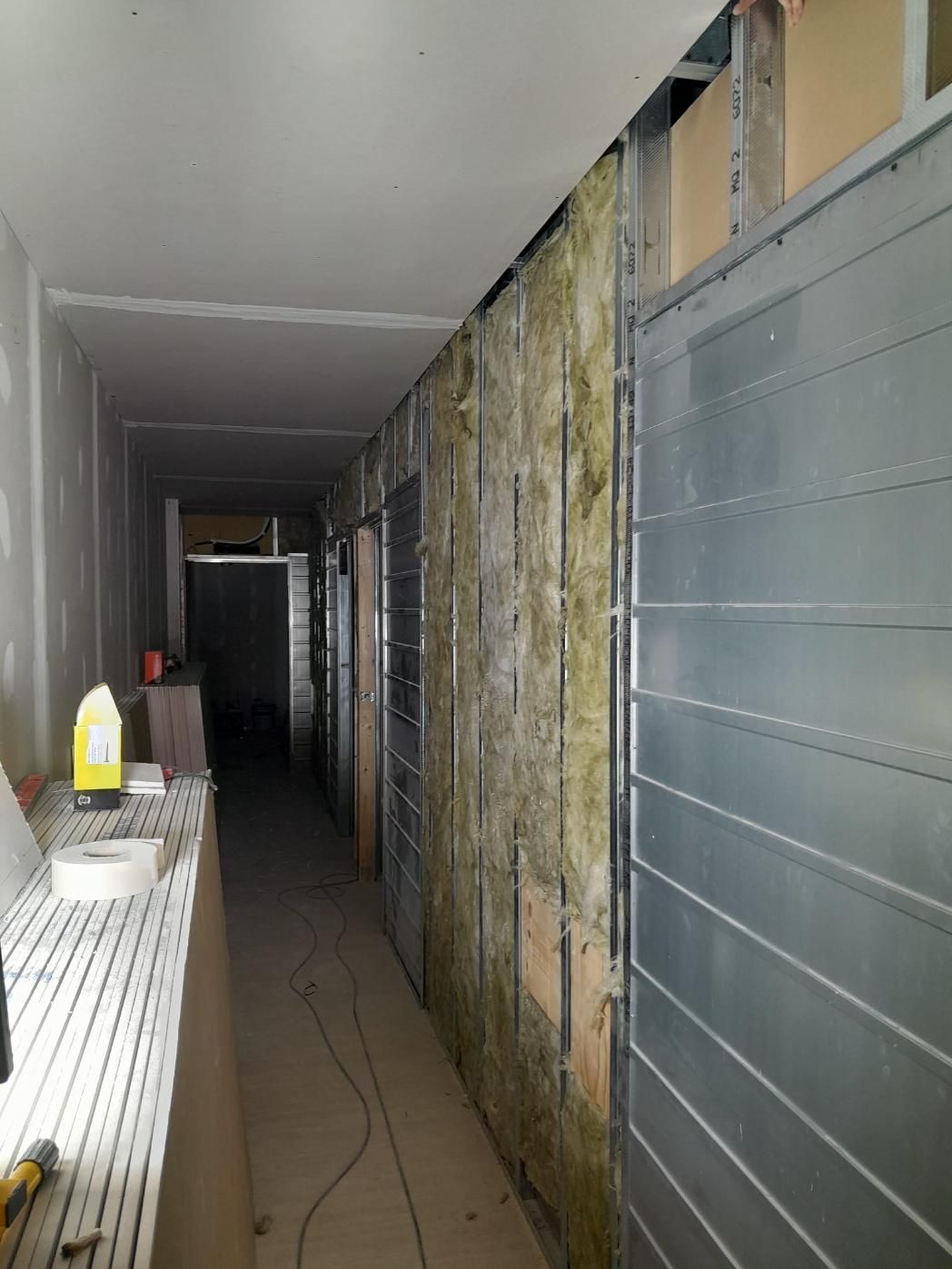 Un pasillo en construcción con aislamiento expuesto en los montantes de las paredes