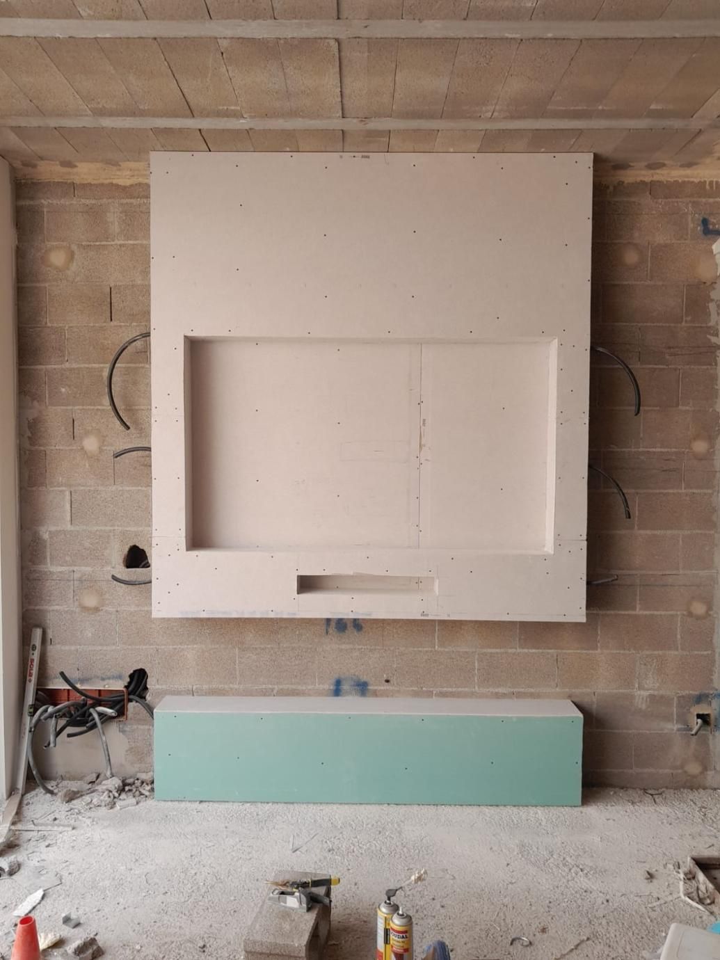 Una obra en construcción que muestra una pared con un soporte de TV de pladur hecho a medida, situado encima de un mueble