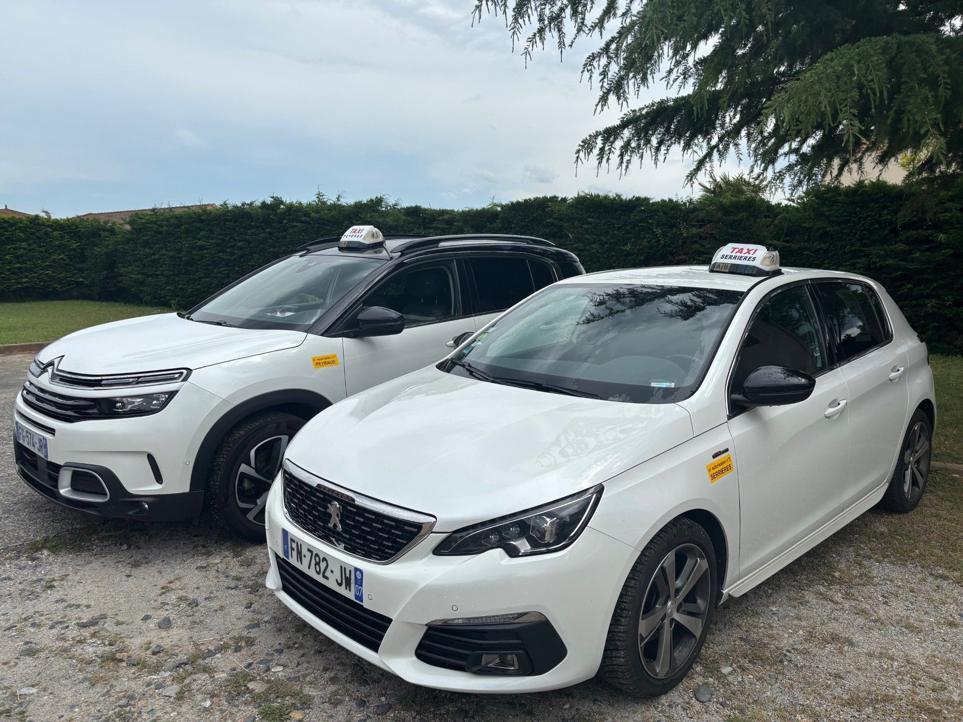 Deux taxis blancs stationnés à l'extérieur, gyrophares allumés.
