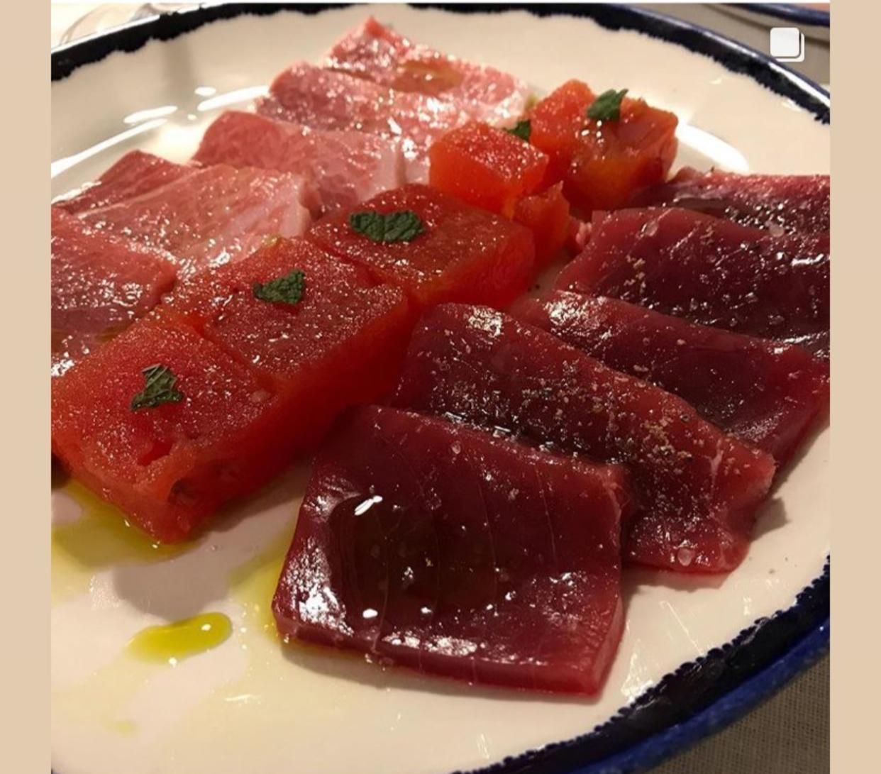 Un plato blanco cubierto con carne en rodajas y tomates.