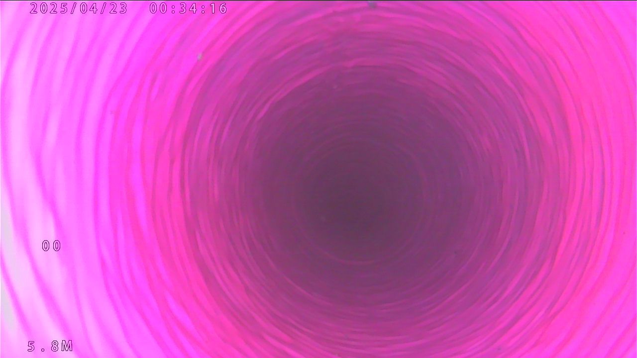 Vue en tons rosés de l'intérieur d'un tuyau ou d'un tube, montrant des motifs circulaires concentriques.