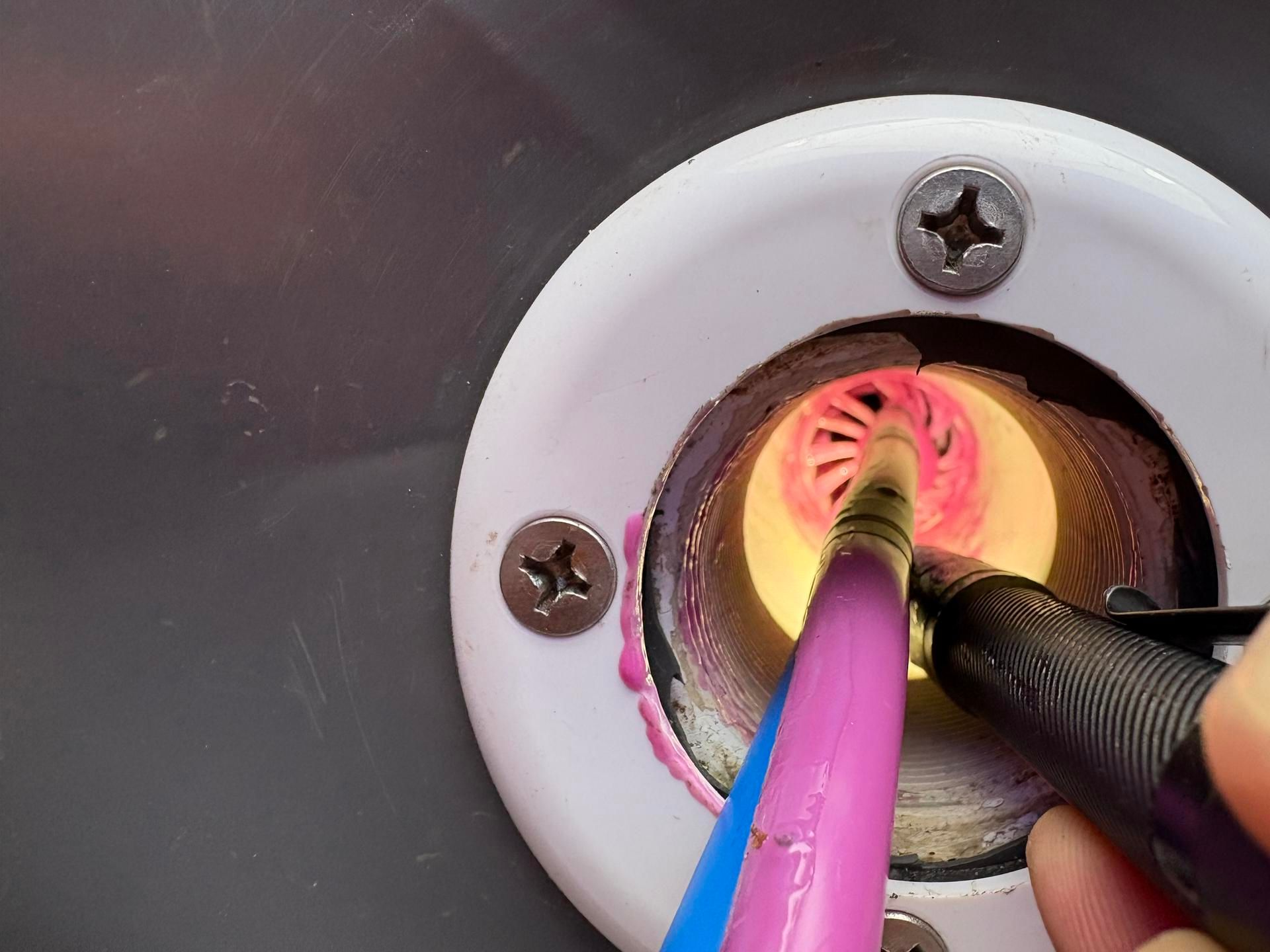 Des outils roses et noirs sont rangés dans un support circulaire blanc. Une lumière vive émane de l'intérieur.